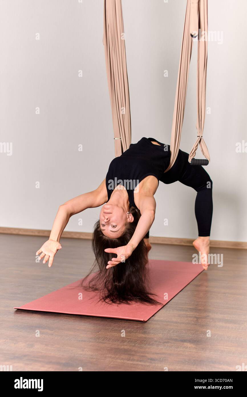 Aerial Position Aerial yoga position captured in minimalist studio. Participant ...