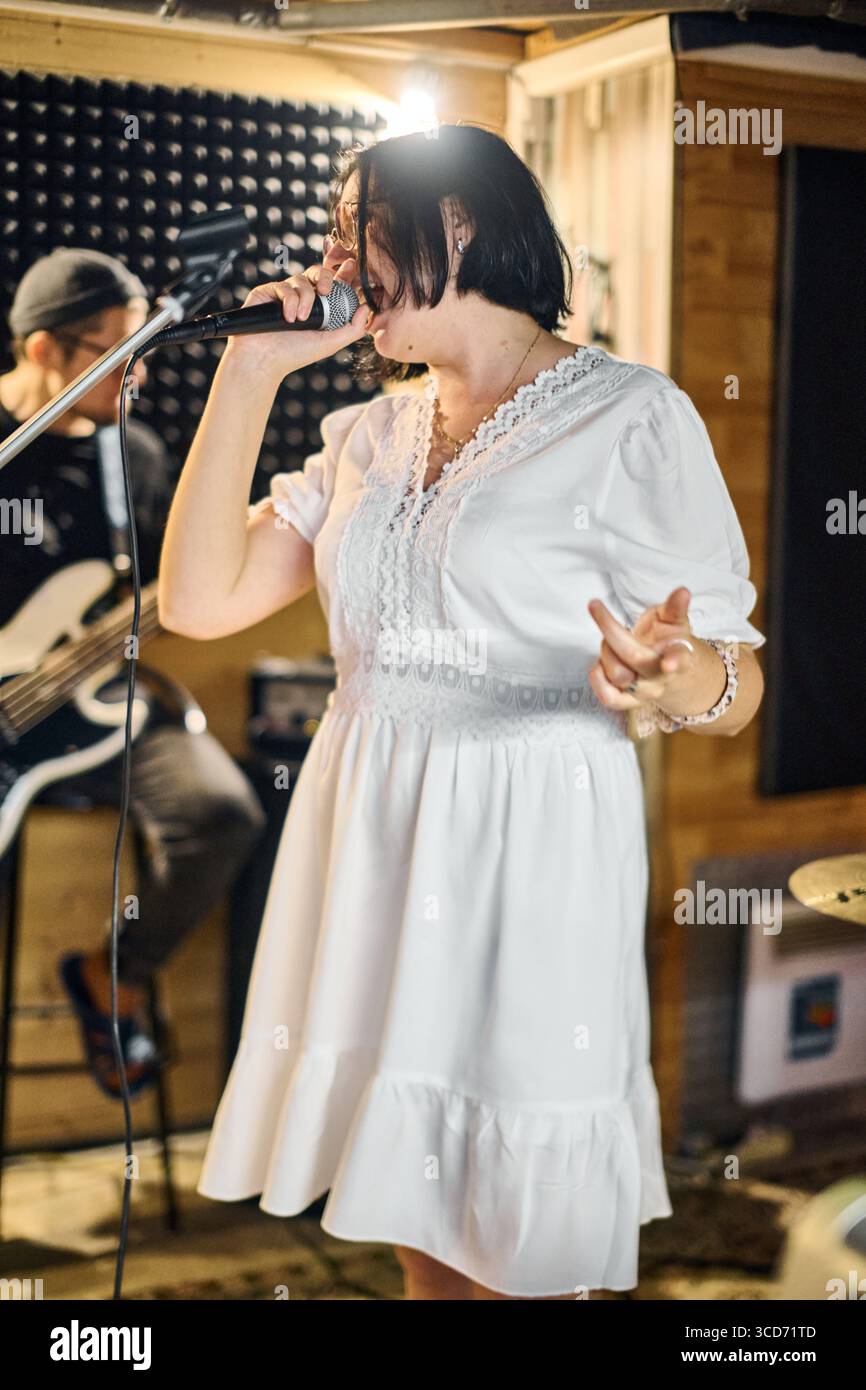 Energetic female vocalist with short dark hair and casual dress ...