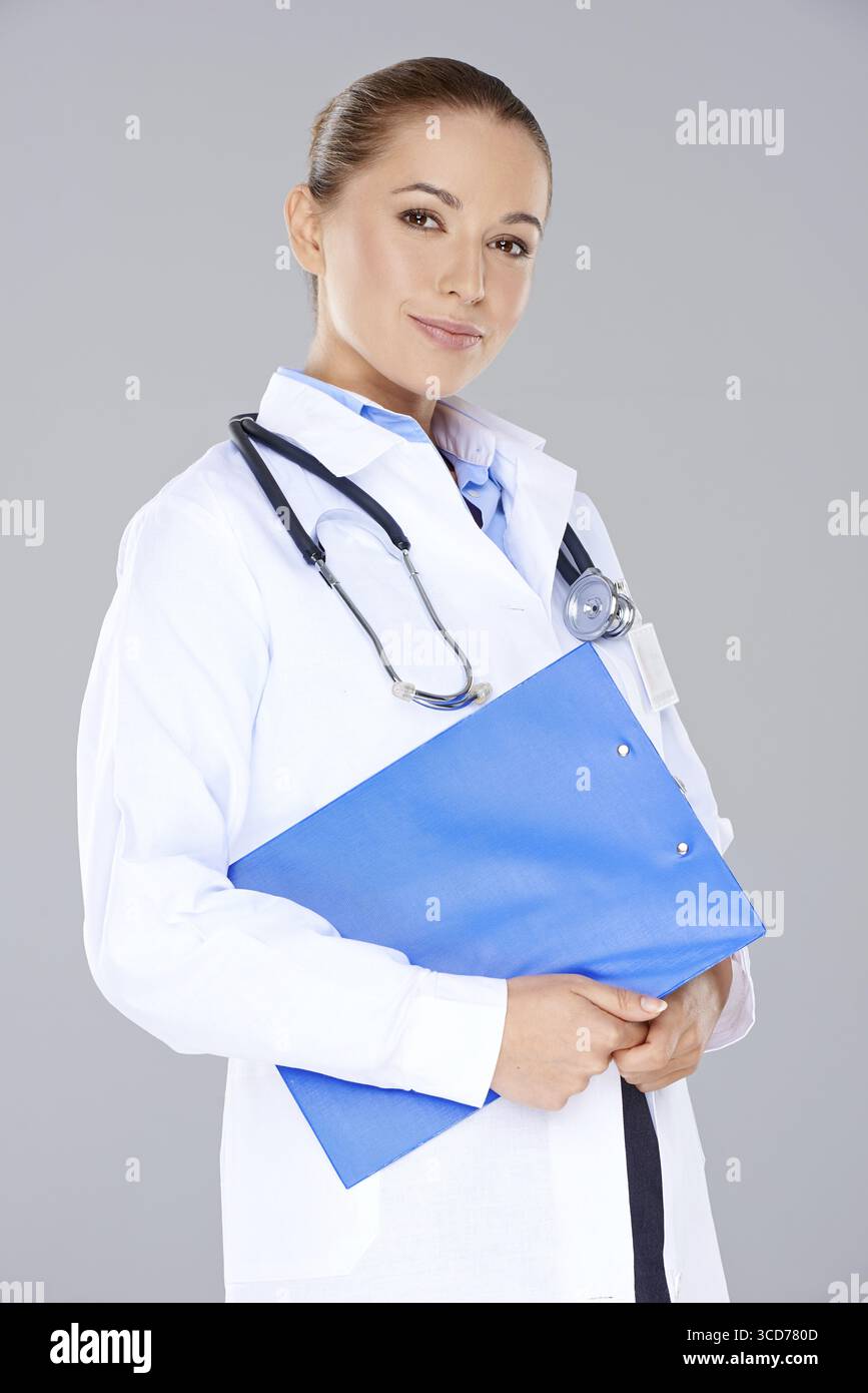 Beautiful young female doctor wearing a stethoscope and clutching a ...