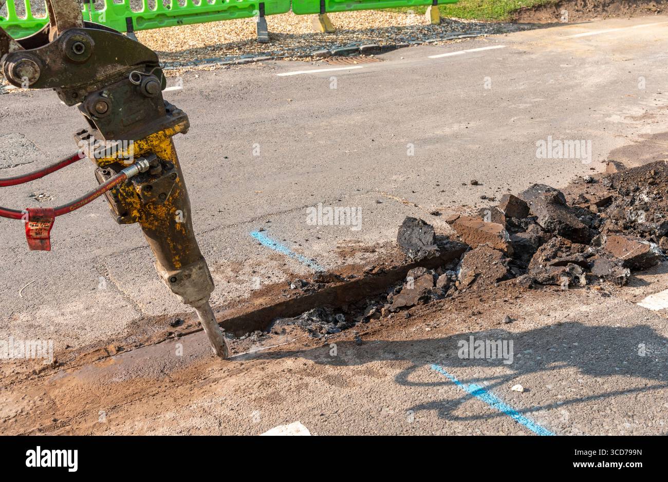 Hampshire England UK.07.08.2025. Hydraulic breaker attachment breaking road surface before trench digging operation for full fibre network cable Stock Photo
