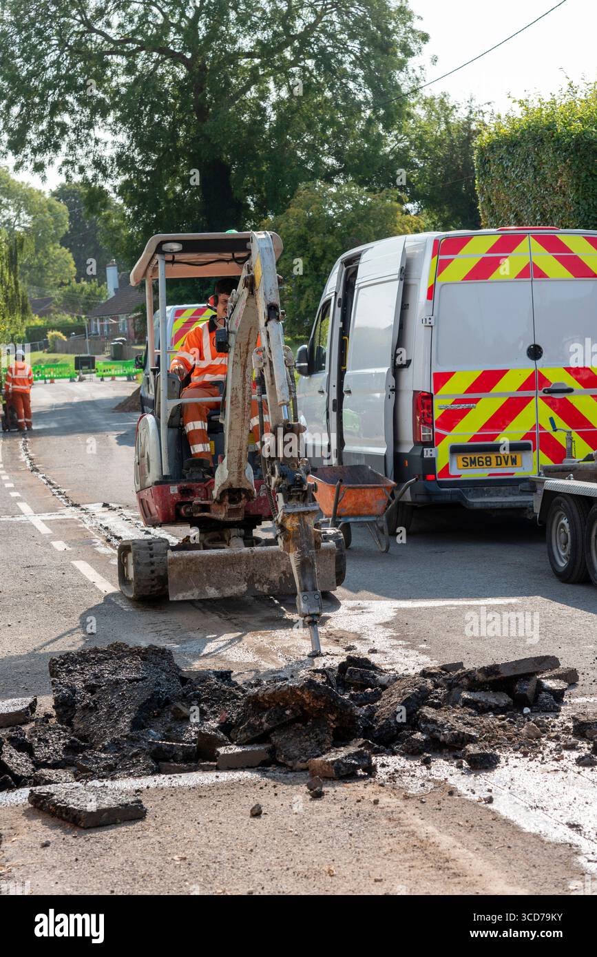 Hampshire England UK.  07.08.2025.   Hydraulic breaker attatchment breaking road surface before trench digging operation for full fibre network cable Stock Photo