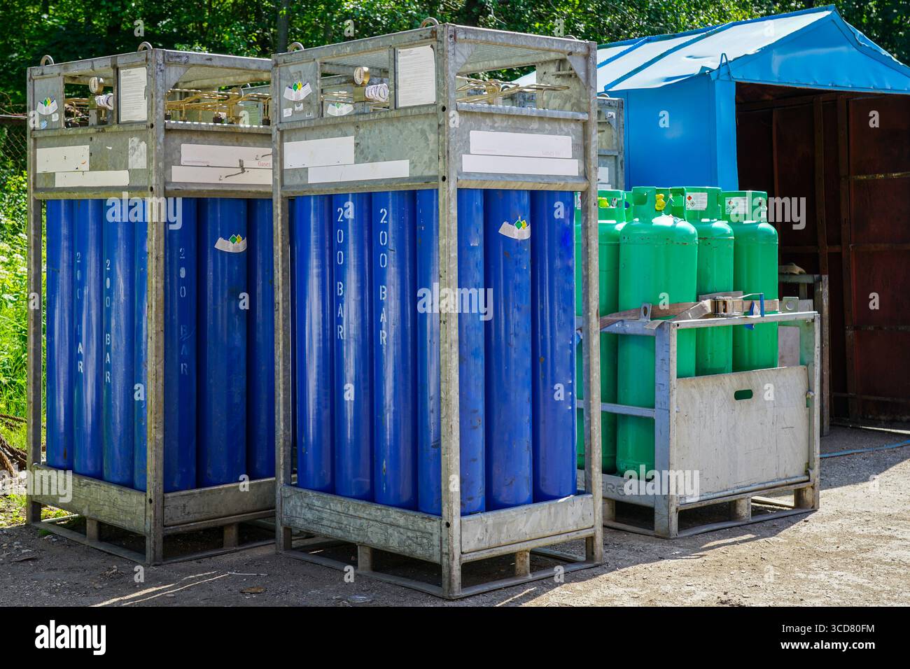 Blue and green industrial gas cylinders stored in metal racks at an ...
