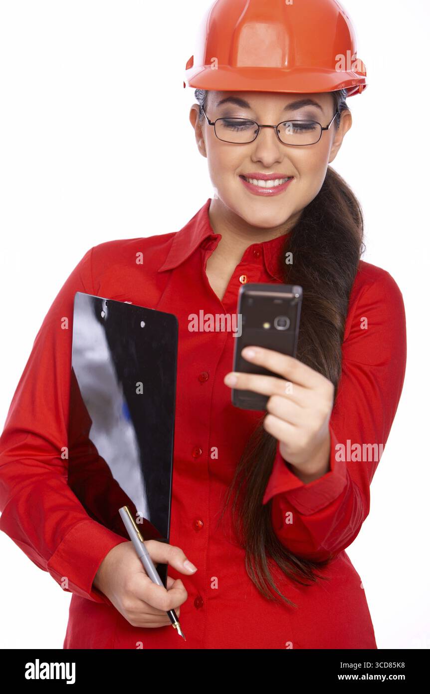 Female architect holding clipboard, using cell phone Stock Photo