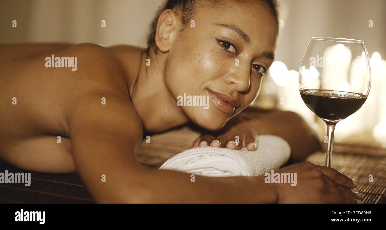 Young woman in spa salon enjoying a glass of red wine Stock Photo