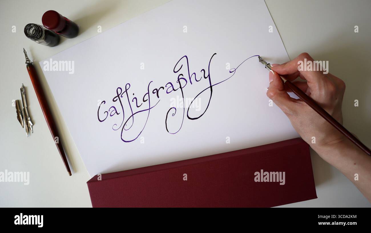 Photo of calligraphy process. Woman's hand writing word Calligraphy ...