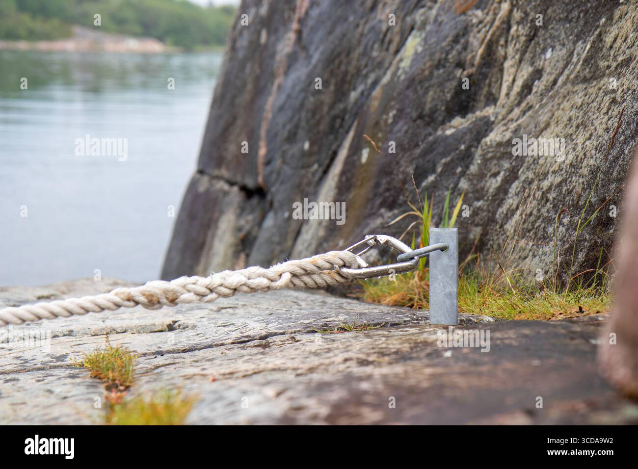 Boat moored to coastal rocks using stain stakes. A rustic maritime ...