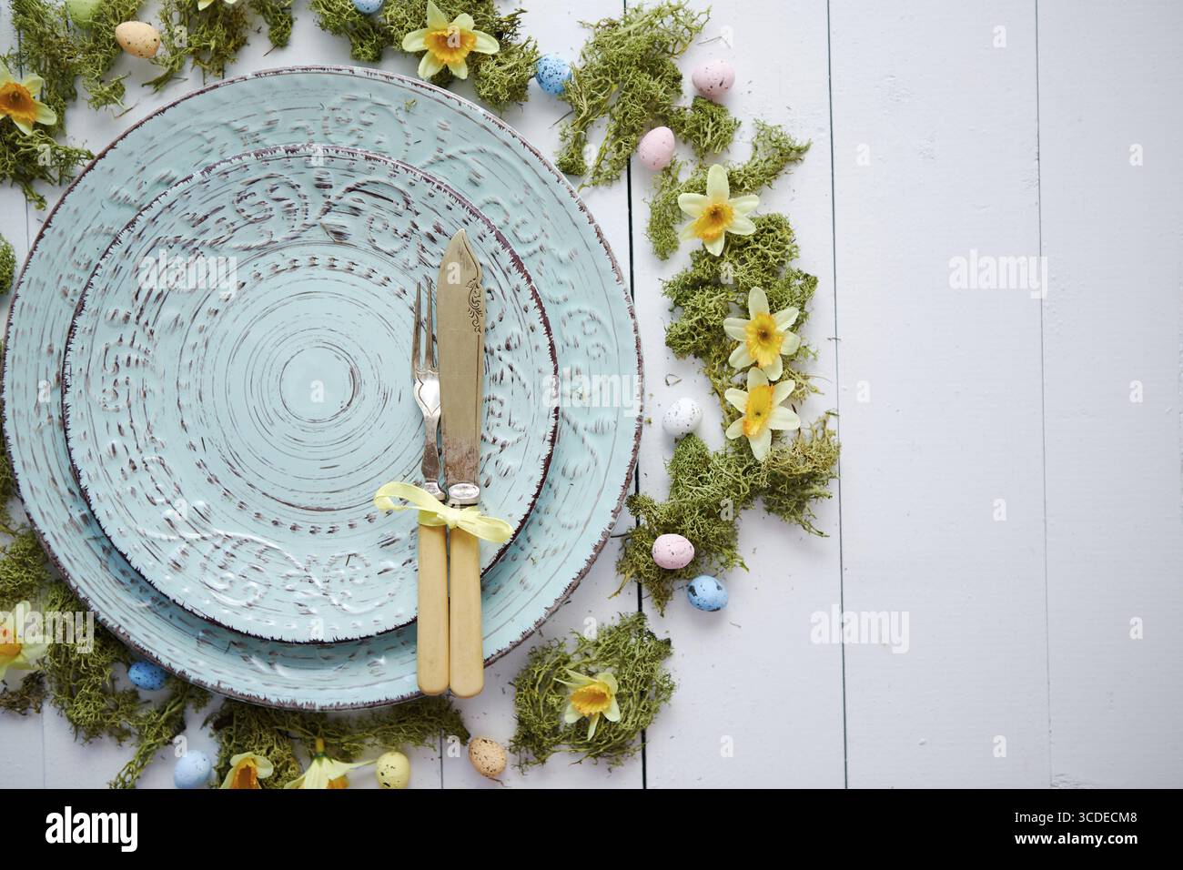 Easter table setting with flowers and eggs. Empty decorative ceramic plates. Rustical dishware. View from above Stock Photo
