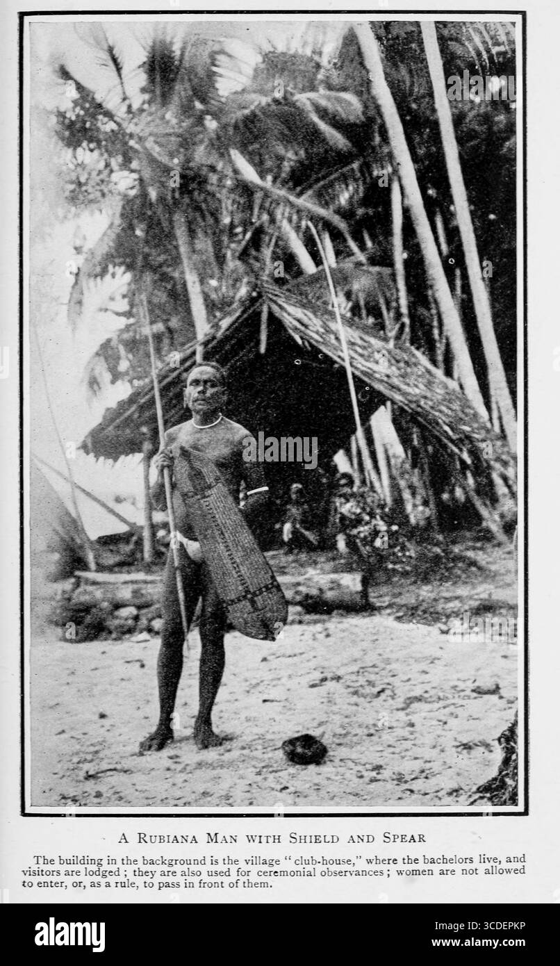 A Rubiana Man with Shield and Spear The building in the background is the village club-house, where the bachelors live and visitors are lodged ; they are also used for ceremonial observances ; women are not to enter, or, as a rule, to pass in front of them. from The ways of the South Seas savage : a record of travel & observation amongst the savages of the Solomon Islands & primitive & coast & mountain peoples of New Guinea Black and white photography by Williamson, Robert W Published 1914 Stock Photo