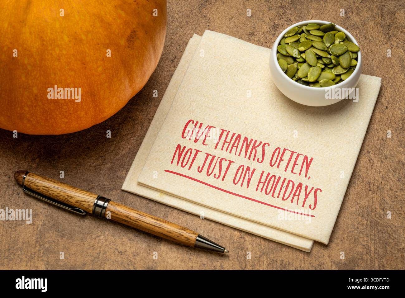 give thanks often, not just on holidays - gratitude and thankfulness concept, Thanksgiving theme, inspirational note on napkin with pumpkin Stock Photo