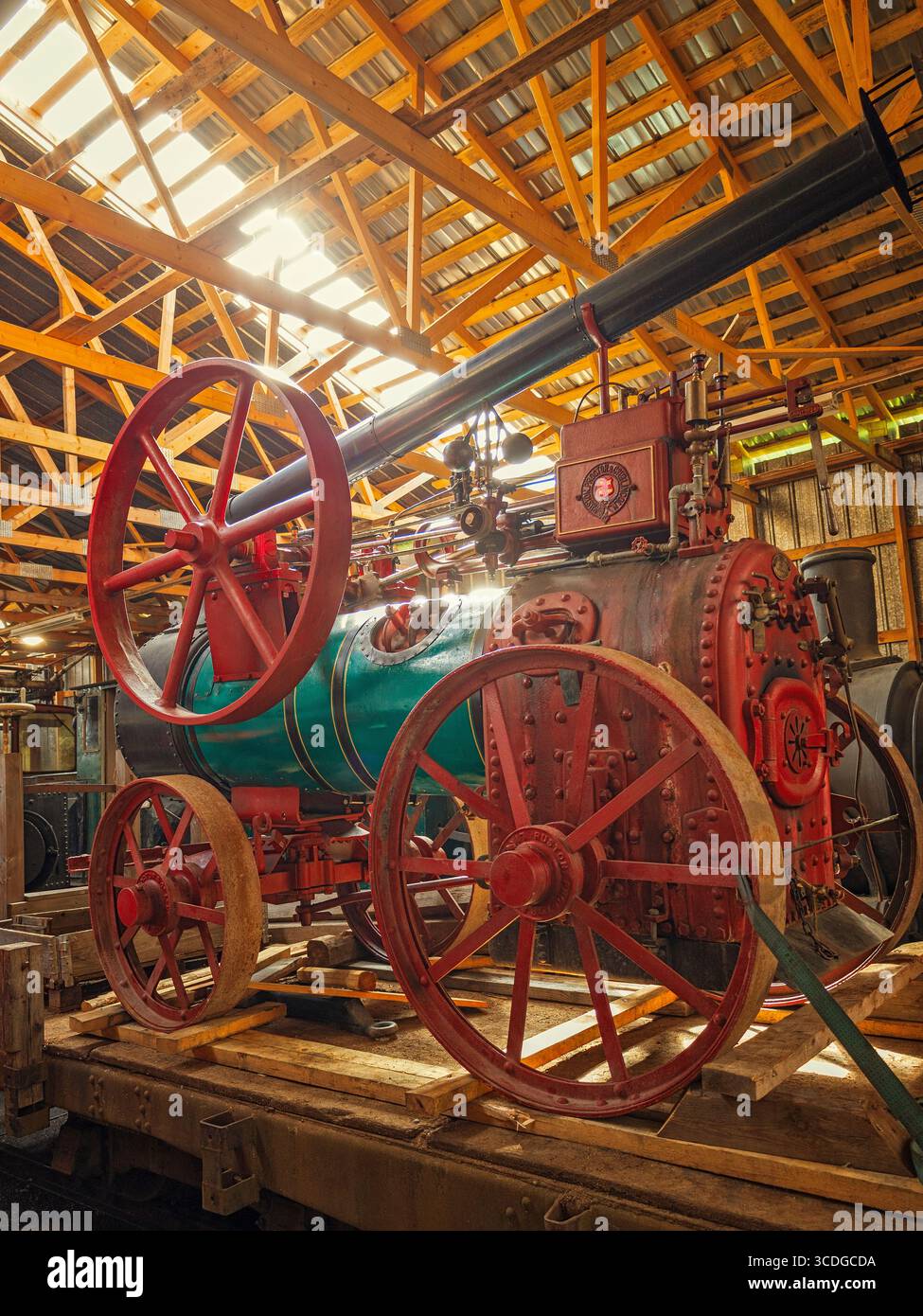 A vibrant, large antique steam machine with prominent red wheels and a ...