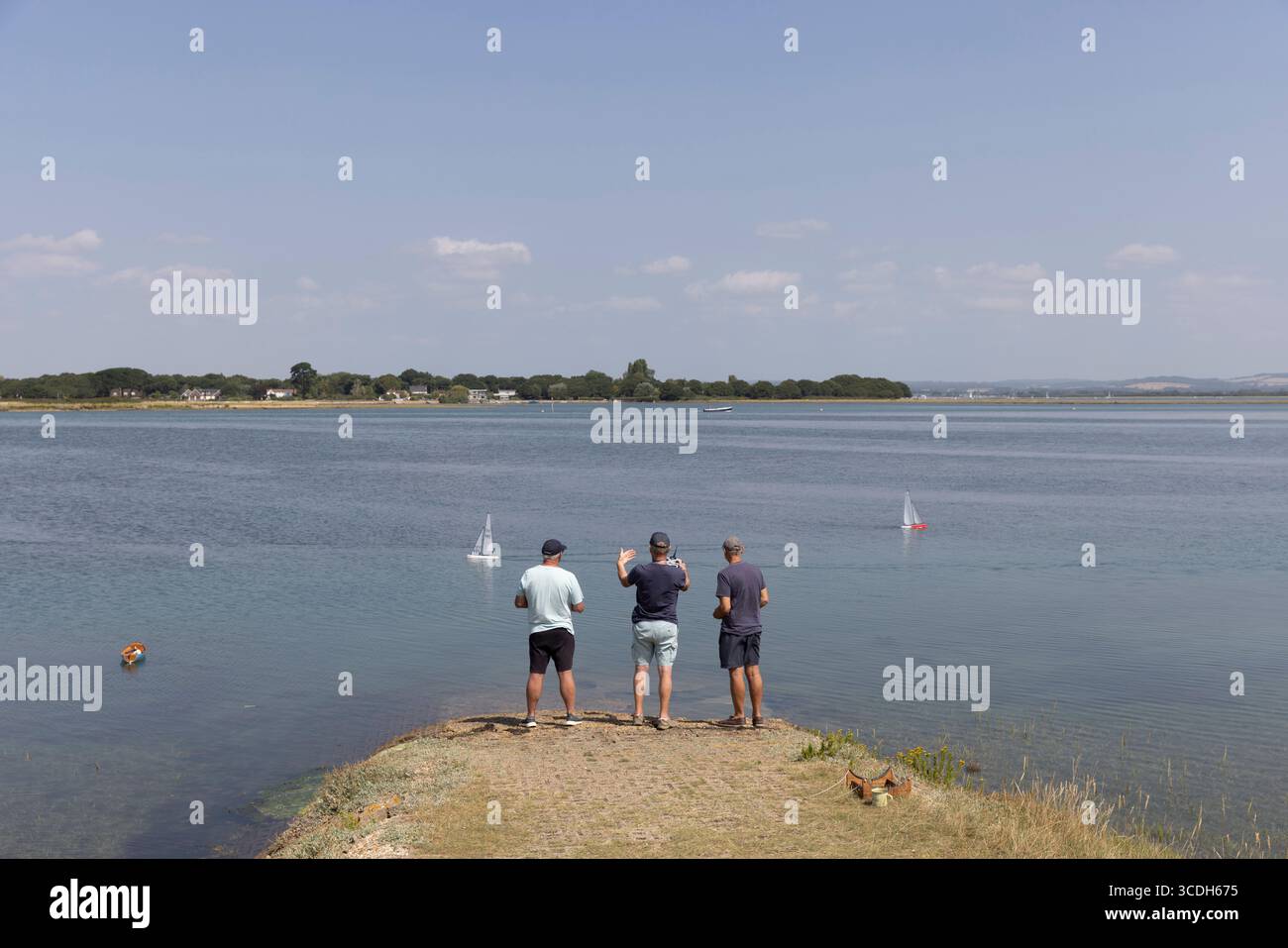Three men standing at the water's edge with their remote controlled ...
