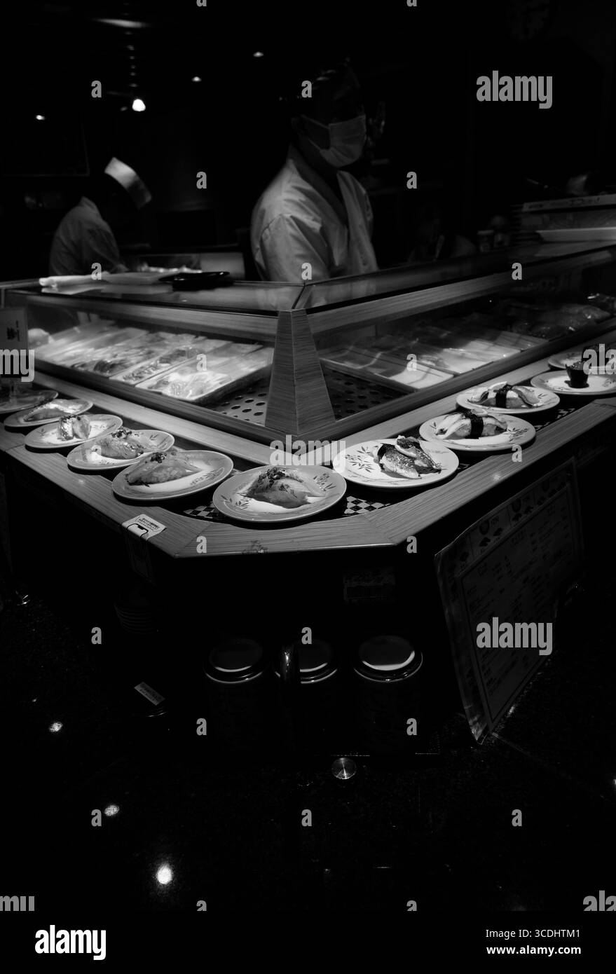 Sushi chef preparing fresh plates at a conveyor belt sushi restaurant in Asakusa, b&w Tokyo Stock Photo