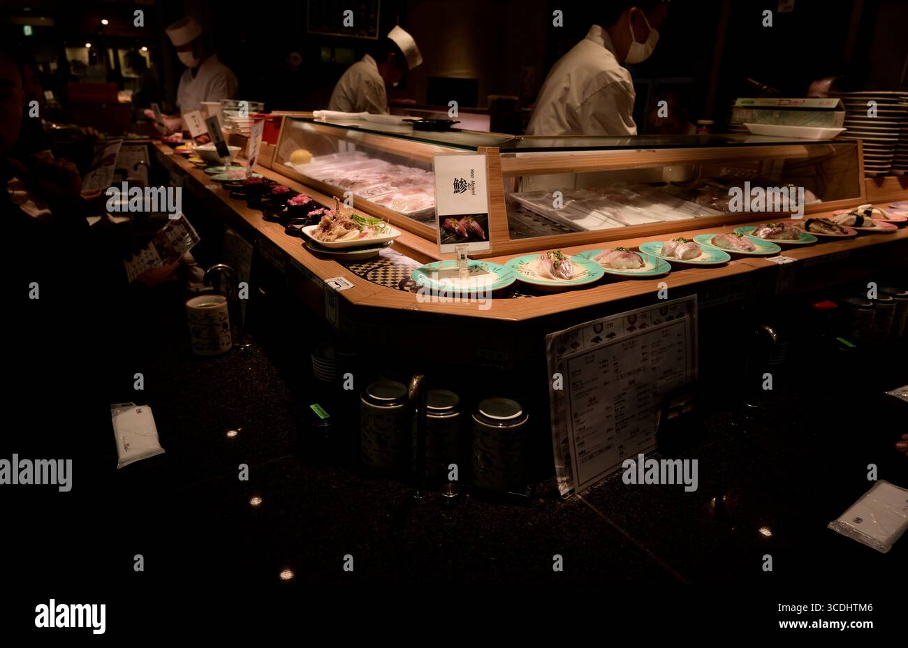 Diners enjoy fresh plates at a bustling conveyor belt sushi bar in Asakusa, Tokyo Stock Photo