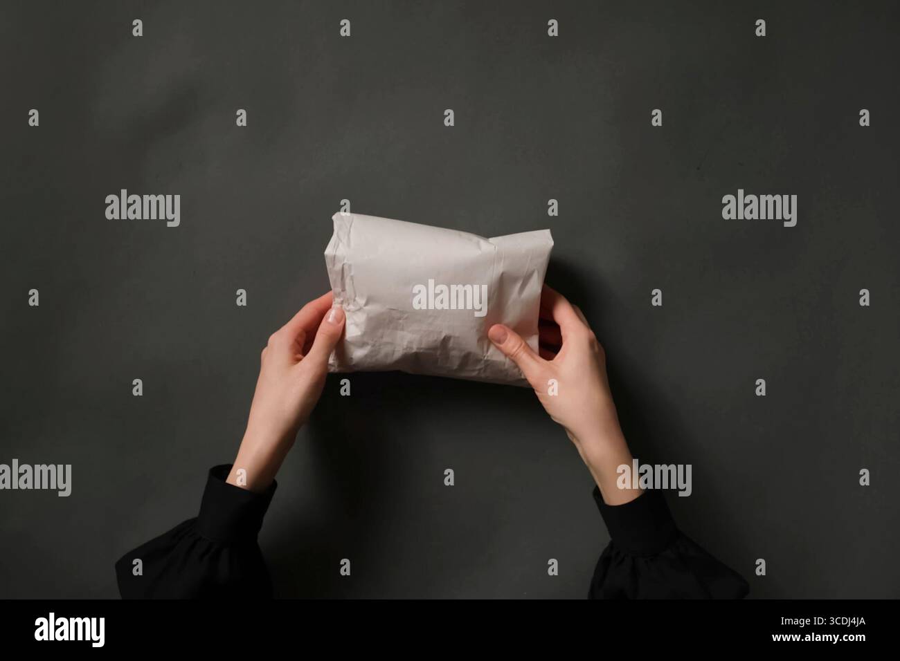 Female Hands Holding Paper Bundle on Dark Gray Table Stock Photo