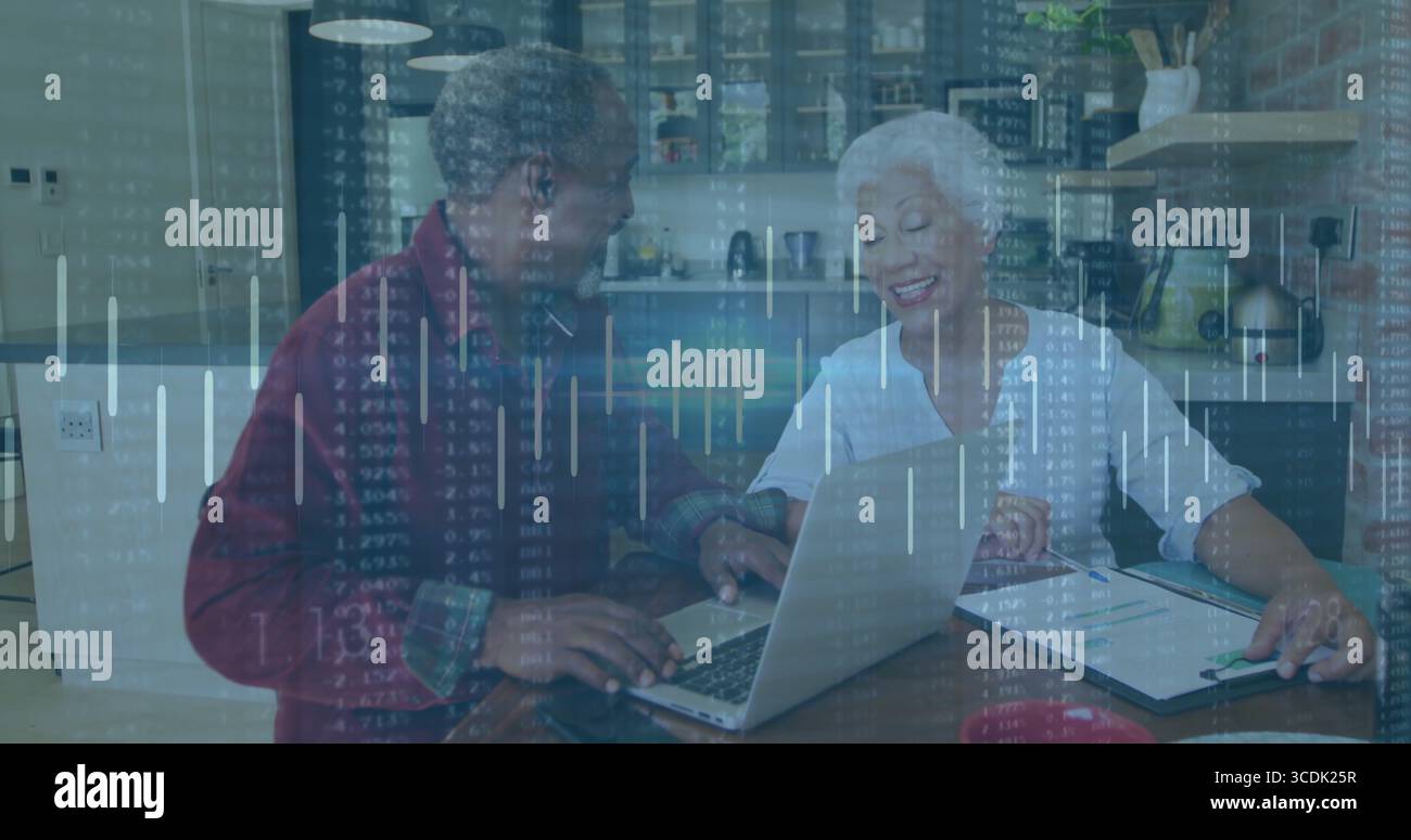 Senior couple reviewing financial data on silver laptop in modern kitchen, with clipboard and pen Stock Photo