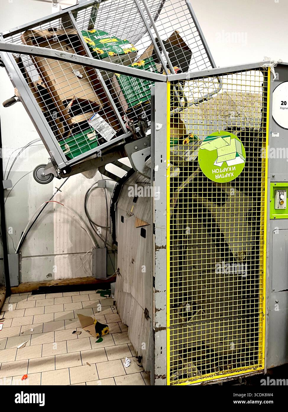 Trolley with cardboard waste being emptied into baling press in supermarket warehouse, recycling, retail waste management, sustainability - Smartphone Captured Stock Image