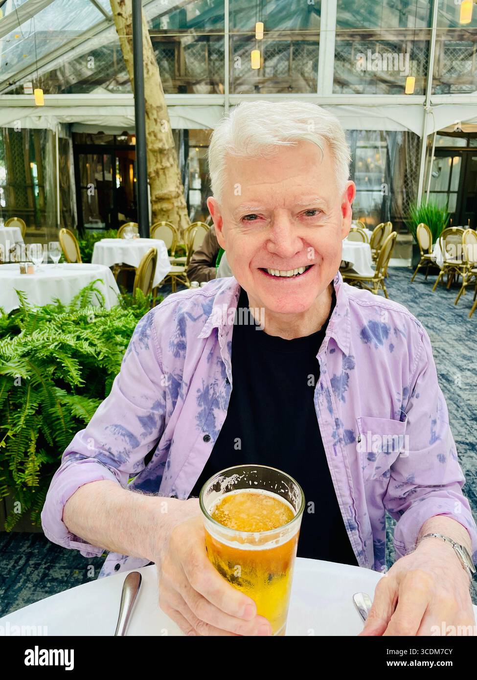 Senir man Outdoor Dining at the Bryant Park Grill Restaurant is festive in summertime, Bryant Park, NYC, USA, 2025 - Smartphone Captured Stock Image