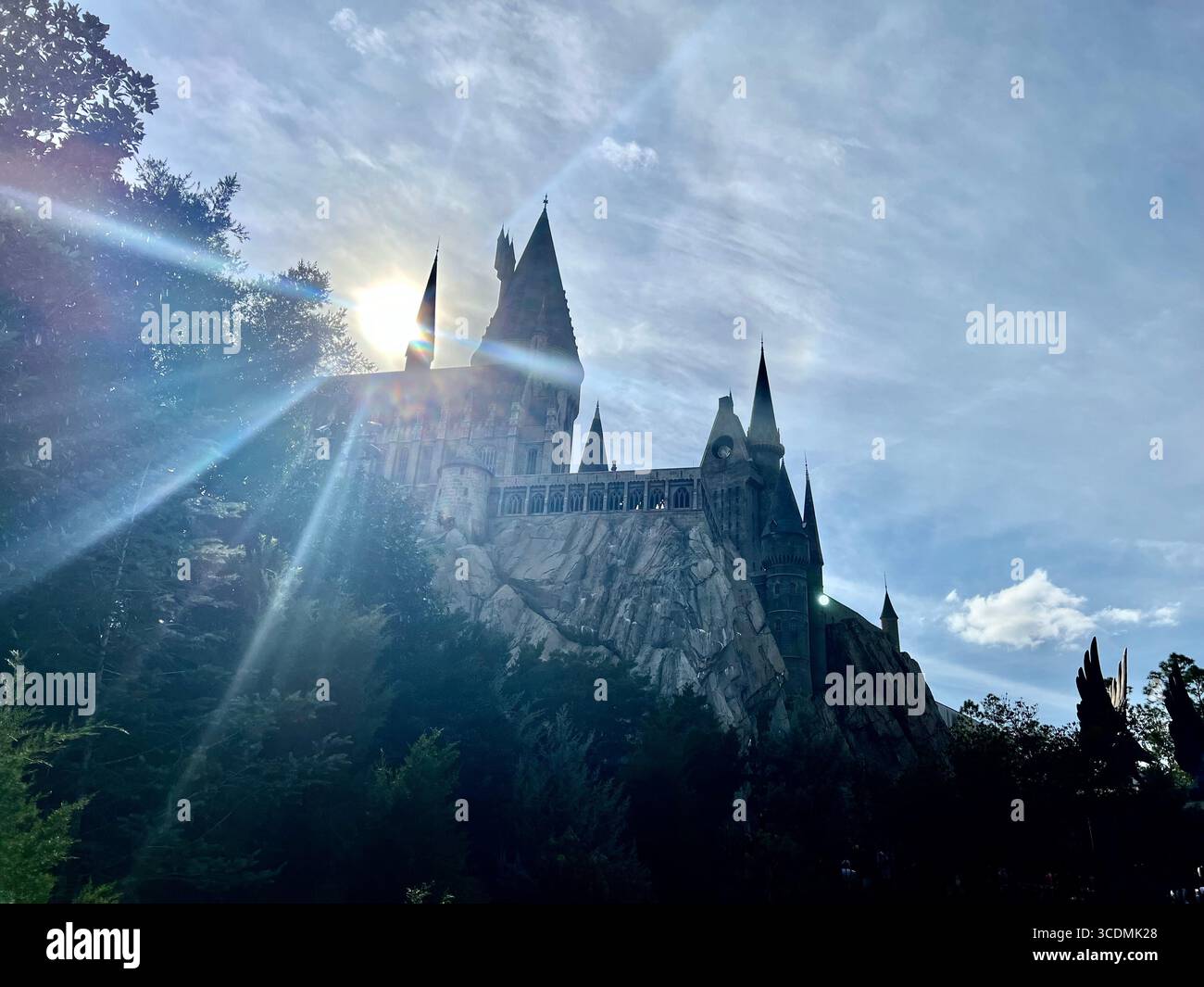 Mid-afternoon sun bursting through a thin layer of clouds over Hogwarts Castle at The Wizarding World of Harry Potter, Universal Orlando. - Smartphone Captured Stock Image