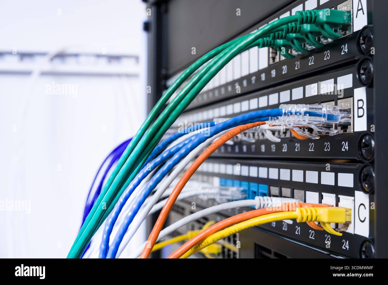 Colorful Ethernet patch cables plugged into patch panel in server rack Stock Photo