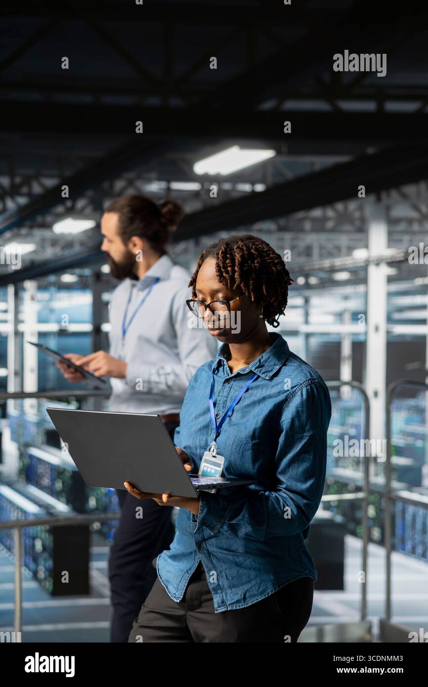 Data center programmer on industrial platform checking lines of code, collaborating on AI tasks. Server room IT specialist visualizing large language model architecture using computer. Stock Photo
