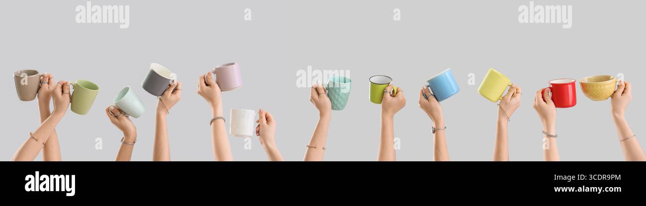 Many hands holding ceramic cups on grey background Stock Photo