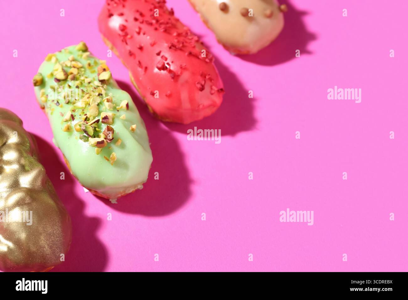 Delicious glazed eclairs on pink background Stock Photo