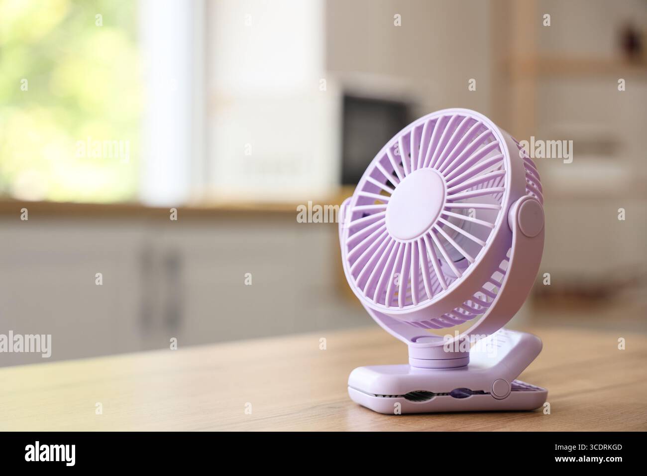 Lilac mini fan on table in kitchen, closeup Stock Photo