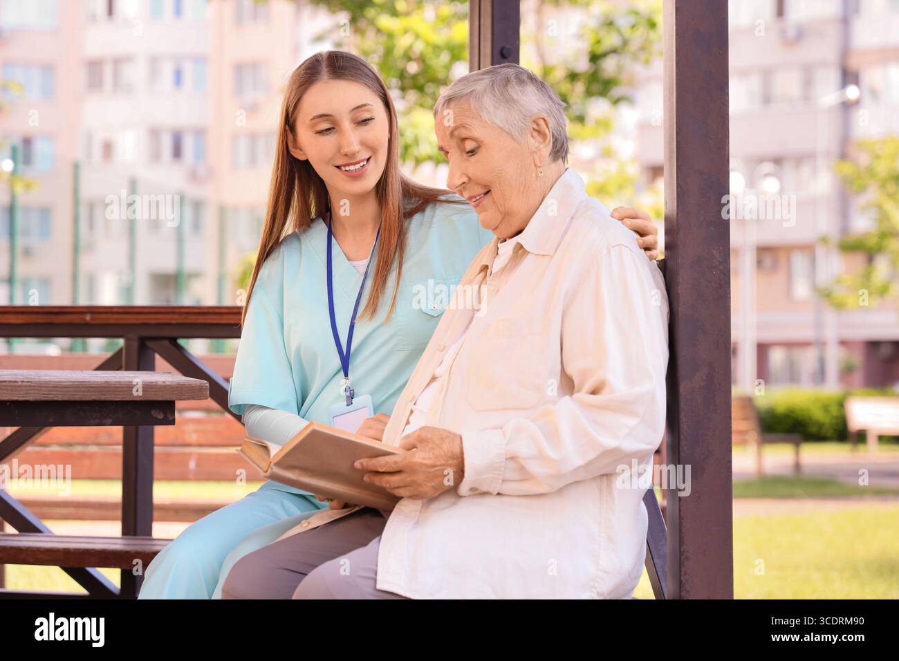Senior woman with nurse reading book in gazebo outdoors Stock Photo