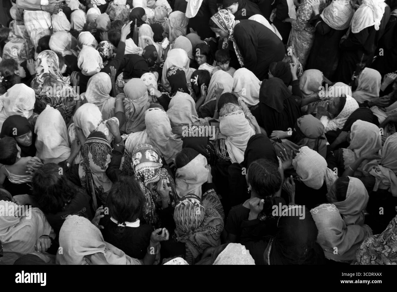 Rohingya refugees crowd around a relief truck at a Cox's Bazar camp entrance. Stock Photo