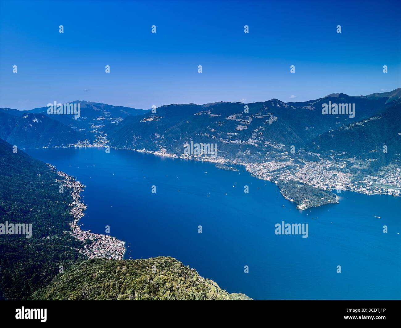 Aerial view of deep blue lake surrounded by lush green mountains and ...