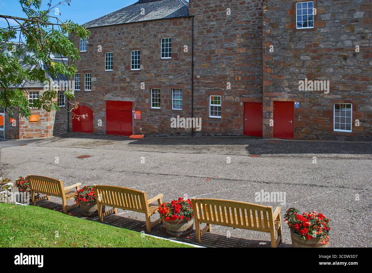 Glenmorangie distillery Tain Ross-shire Scotland  wooden seats begonia flowers in barrels and the main buildings in summer Stock Photo