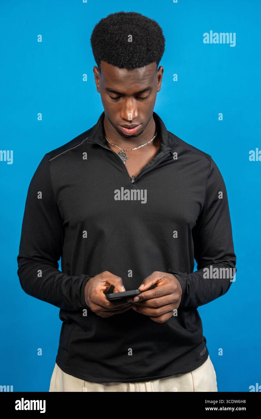 Focused young man using smartphone, browsing internet, chatting online, or playing mobile game Stock Photo