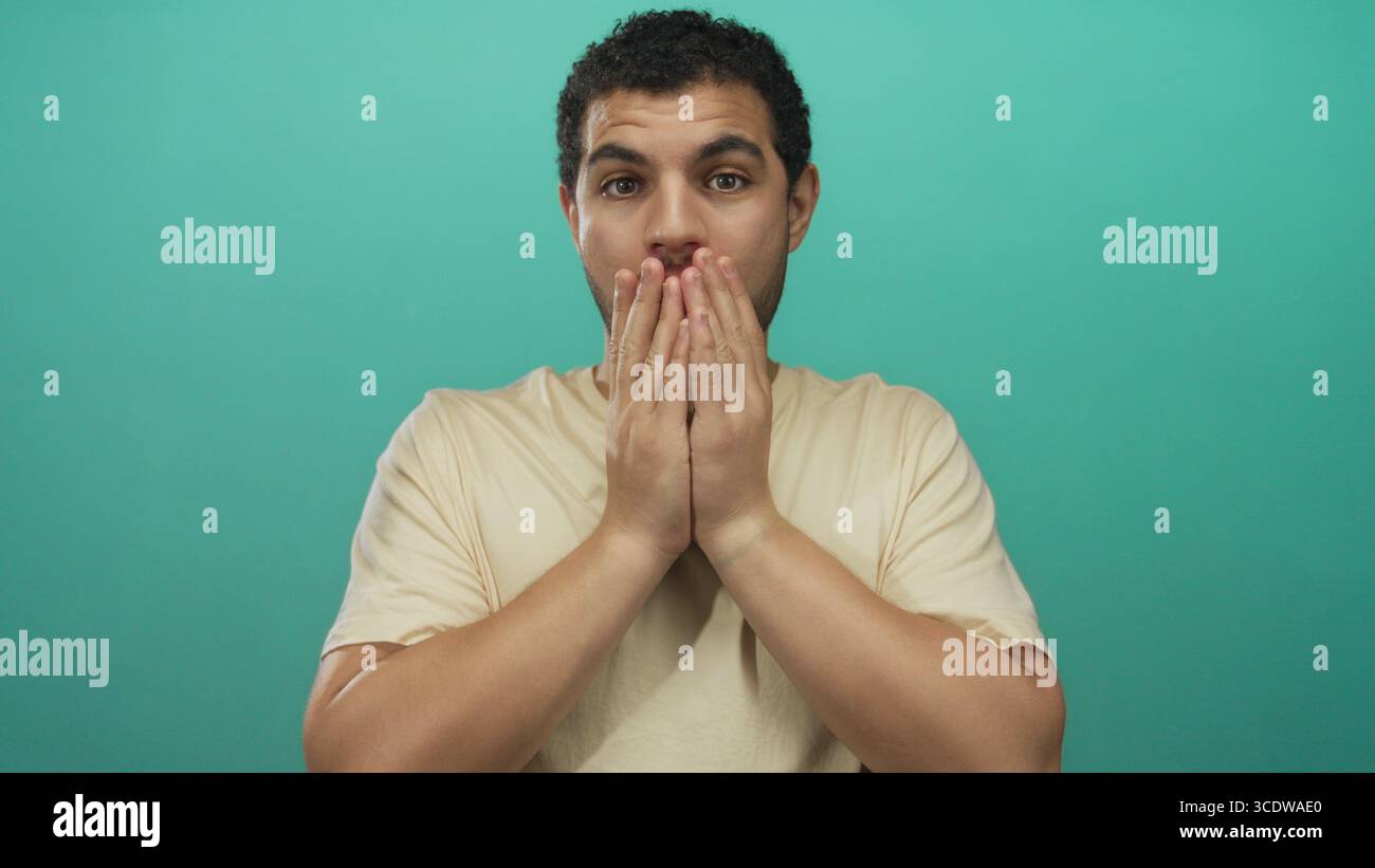 Man holds cheeks with both hands and opens mouth wide against a ...