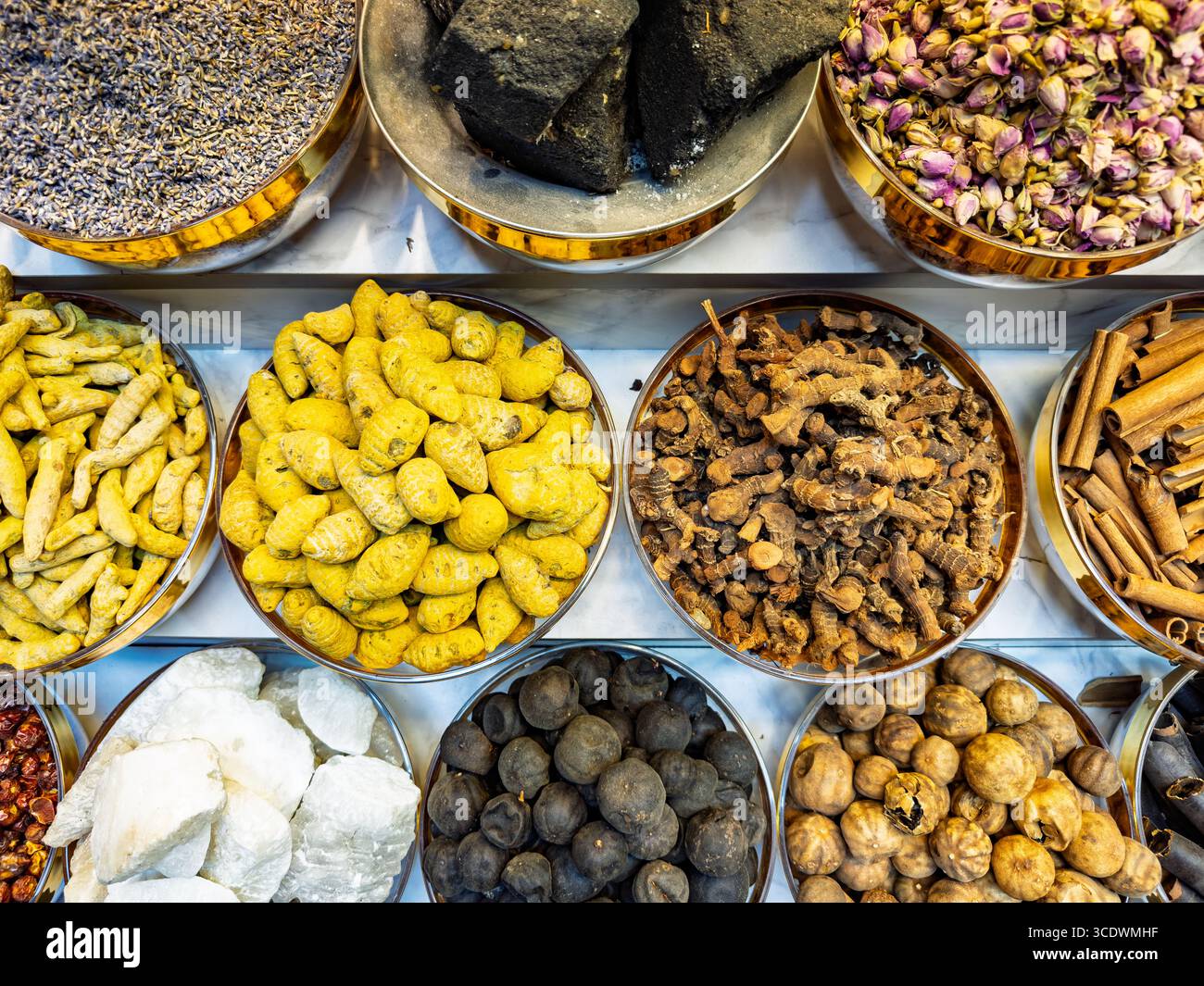 top view Colourful assortment of various spices & herbs in metallic bowls at market stall viewed from above, spice souk, deira creek market, dubai UAE - Smartphone Captured Stock Image