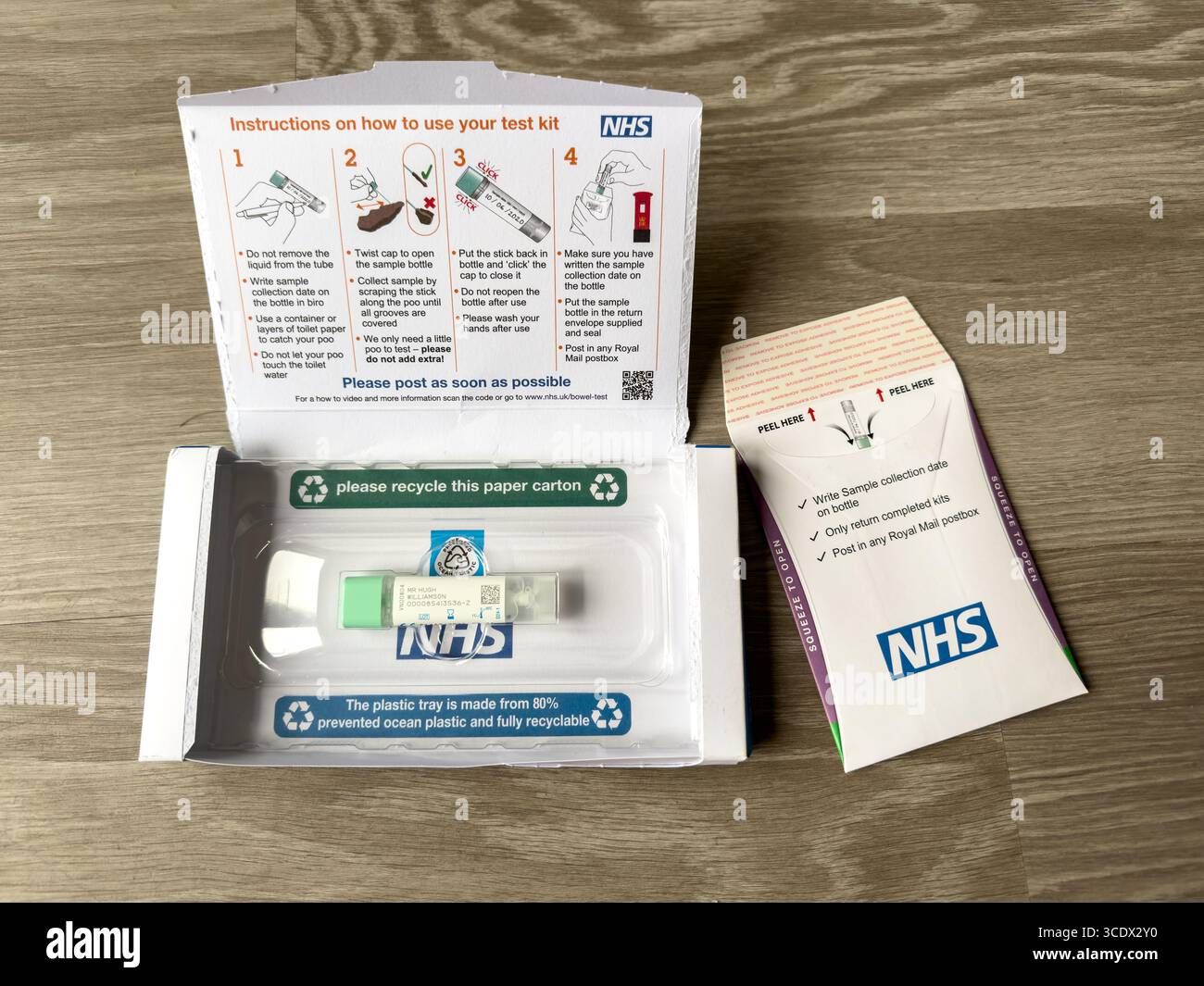 NHS self-test kit for bowel cancer on a wooden surface including instructions and screening test components for easy and safe home use - Smartphone Captured Stock Image