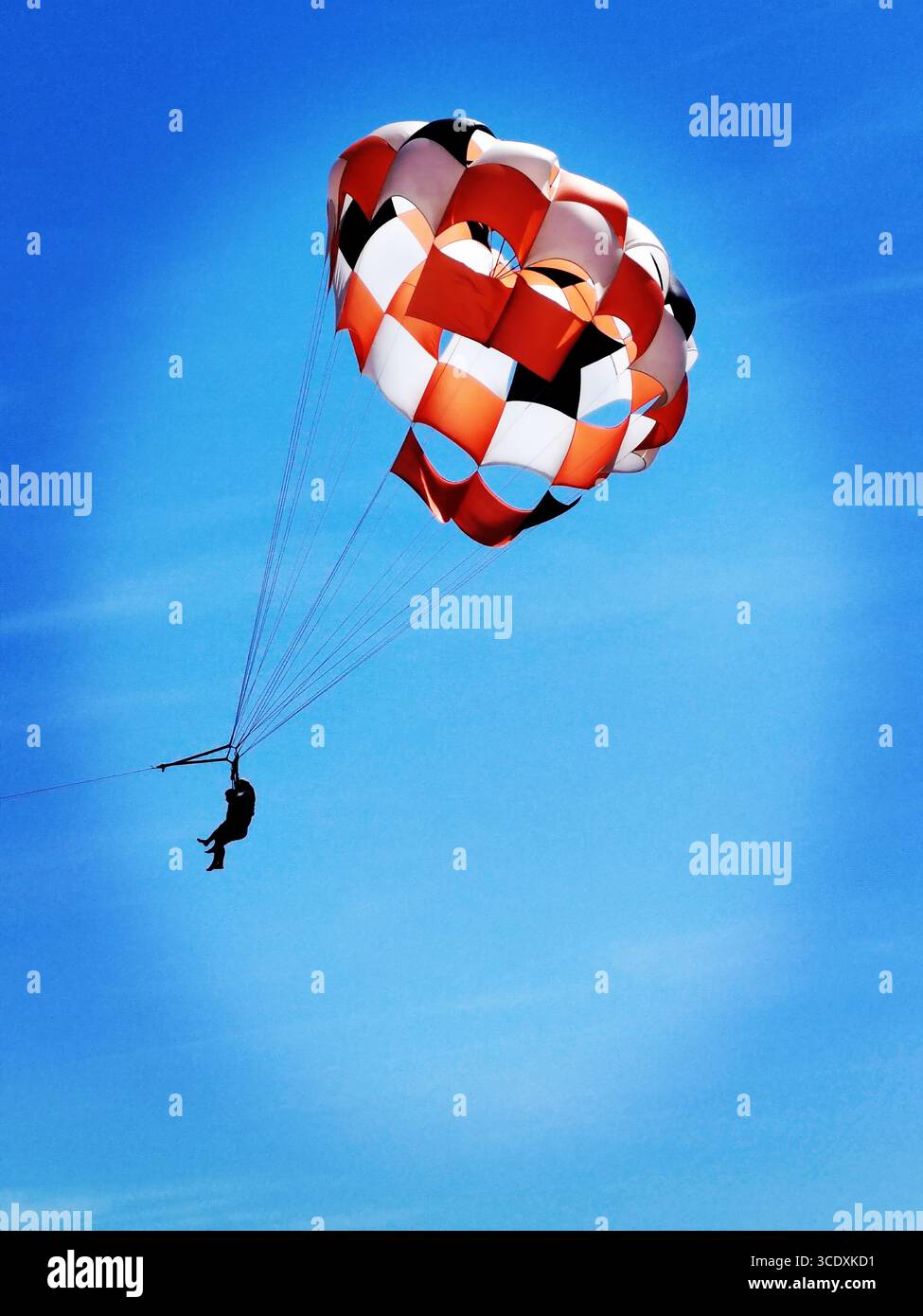 Adventure parasailing over a bright, clear sky, showing a colorful parachute and thrill-seeker in the air. - Smartphone Captured Stock Image