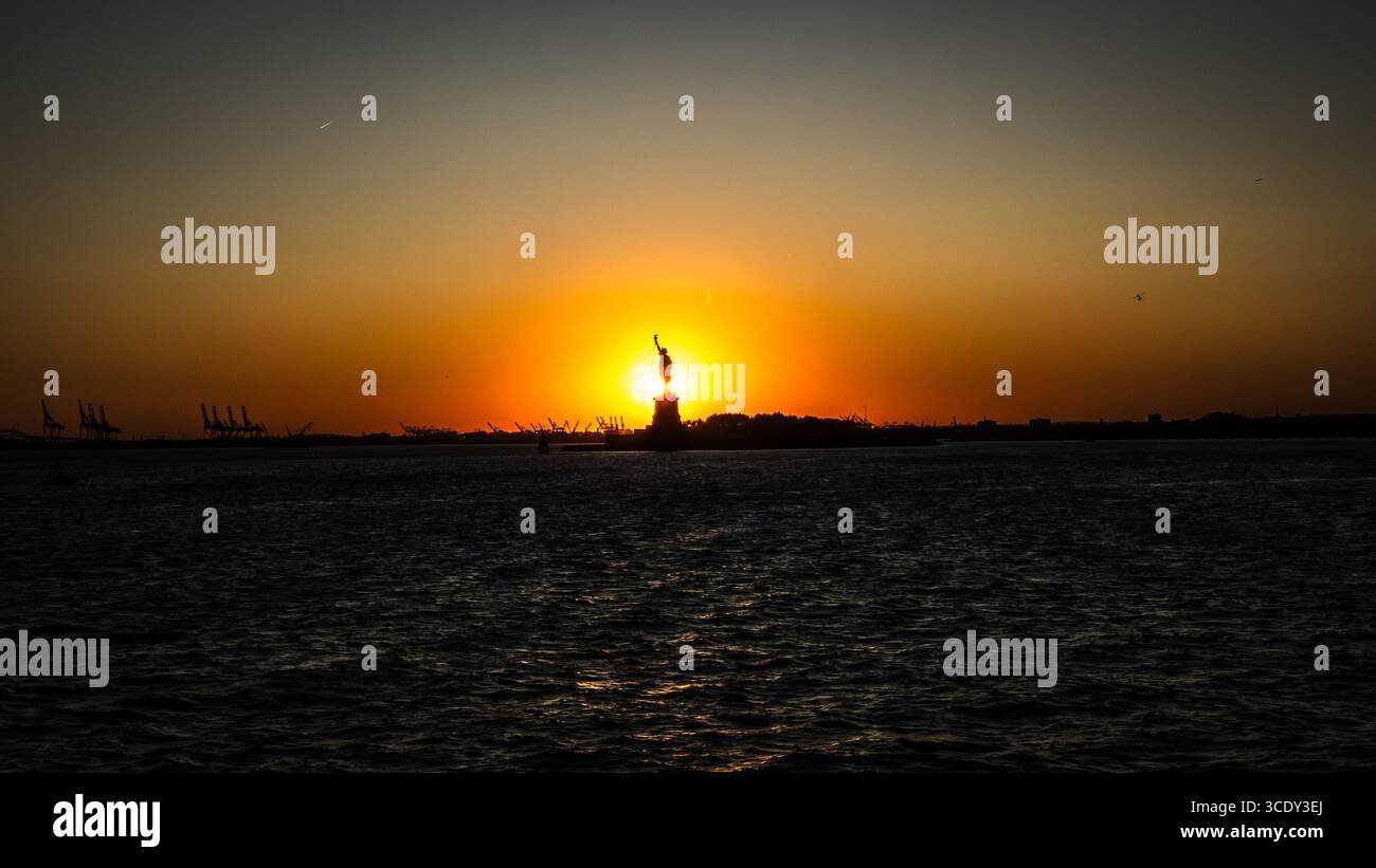 The sun sets behind The Statue of Liberty as seen from the Staten Island Ferry - Smartphone Captured Stock Image