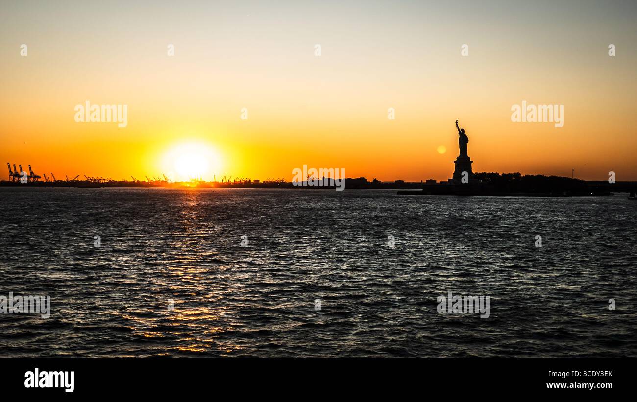 The sun sets behind The Statue of Liberty as seen from the Staten Island Ferry - Smartphone Captured Stock Image