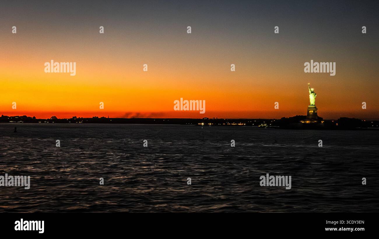 The sun sets behind The Statue of Liberty as seen from the Staten Island Ferry - Smartphone Captured Stock Image