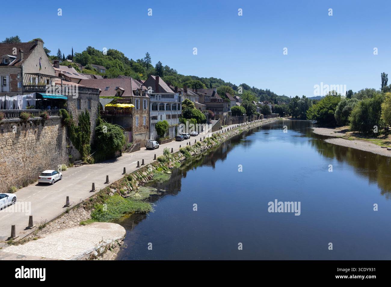 Beautiful summer view of the Vezere River a it passes through the town of Le Bugue in Perigord Noir, Dordogne, France. Clear blue sky, and copy spce a - Stock Image