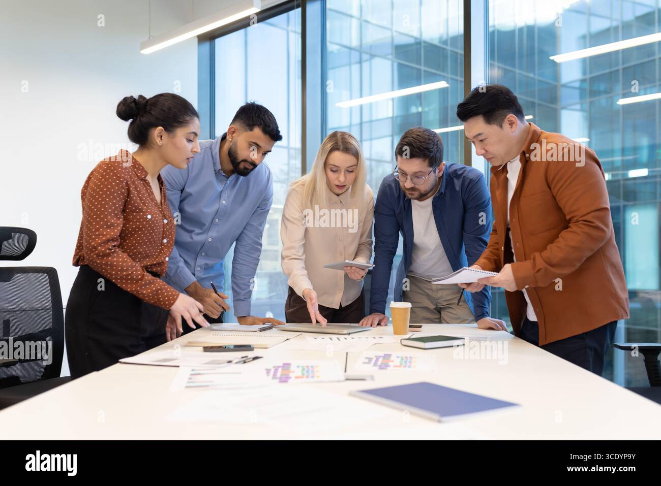 A group of diverse professionals collaborates around a table in a ...