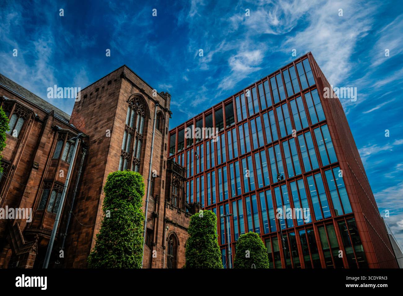 Exterior of John Rylands Research Institute and Library in comparison to modern office blocks, Deansgate Manchester, UK. Stock Photo
