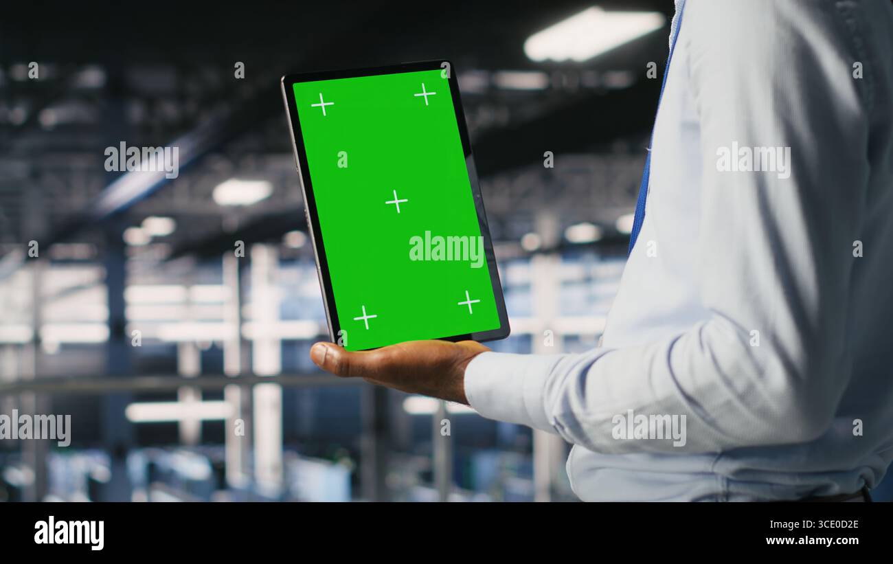 Data center engineers on industrial platform using isolated screen device, collaborating on tasks. Server hub workers visualizing large language model architecture using chroma key tablet Stock Photo