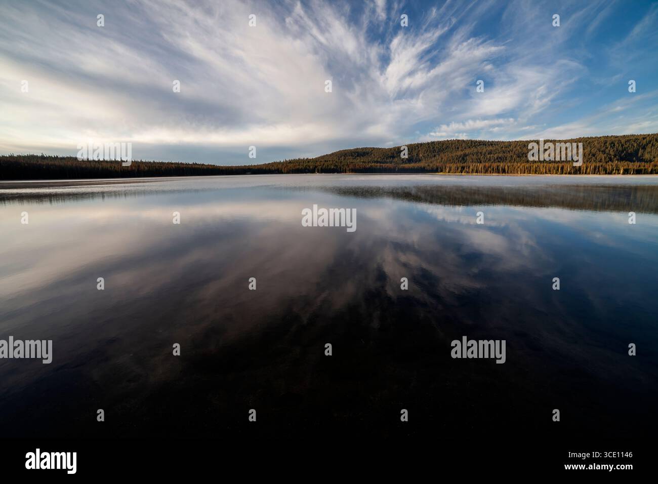 Morning clouds reflect in the calm waters of Medicine Lake in Northern California's Modoc County Stock Photo