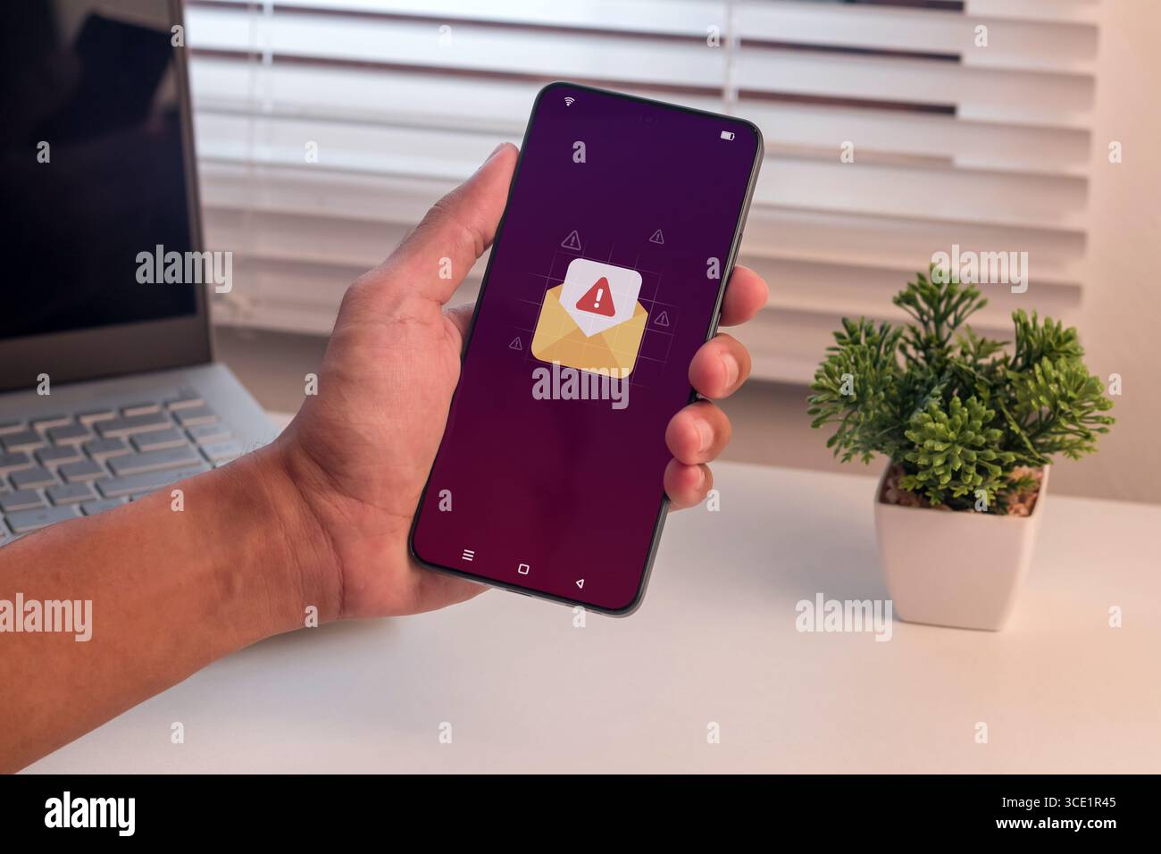 Email or message notification with warning symbol. Man holding a smartphone with email or message spam notification. Stock Photo