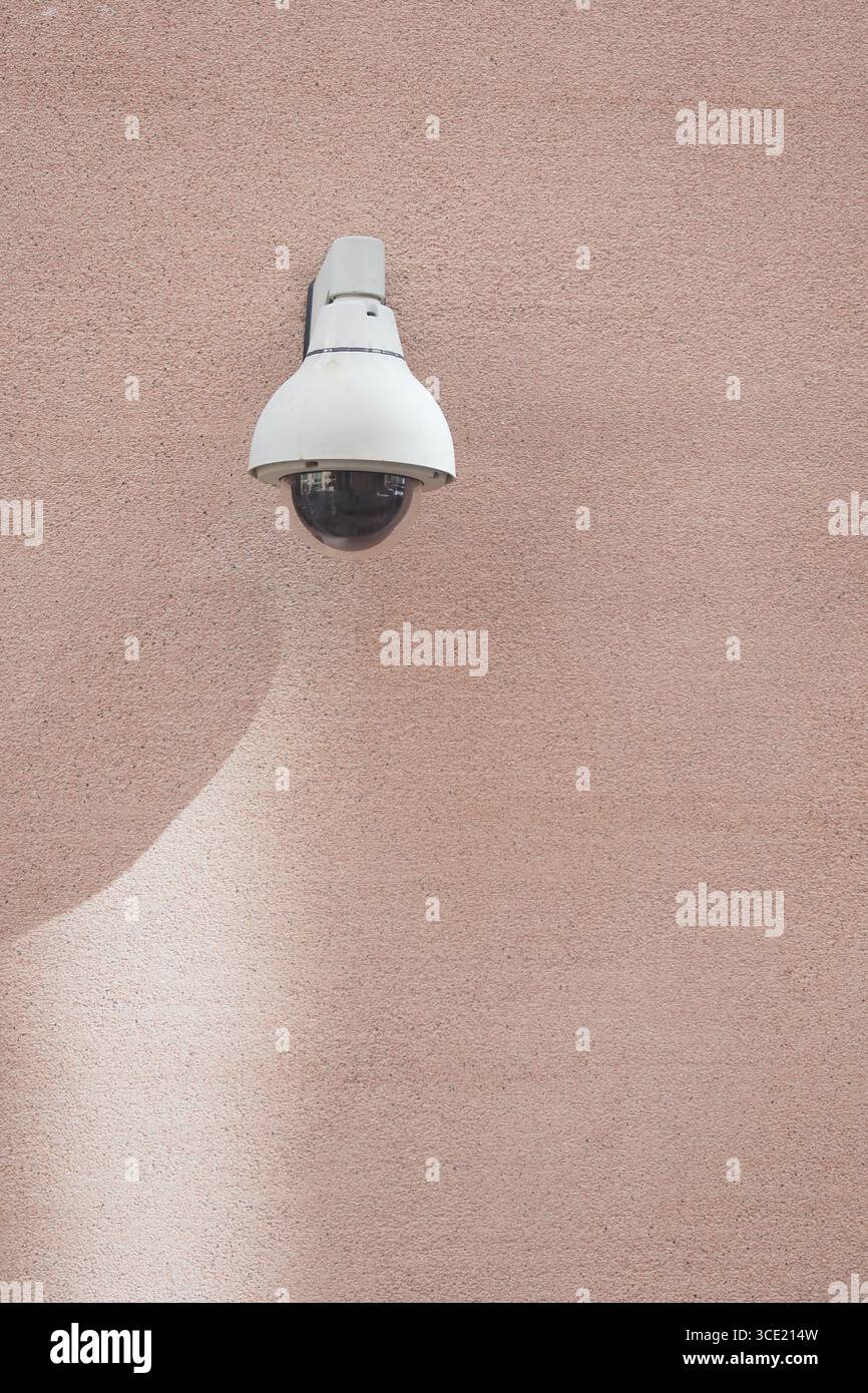Security camera mounted on a textured pink wall Stock Photo