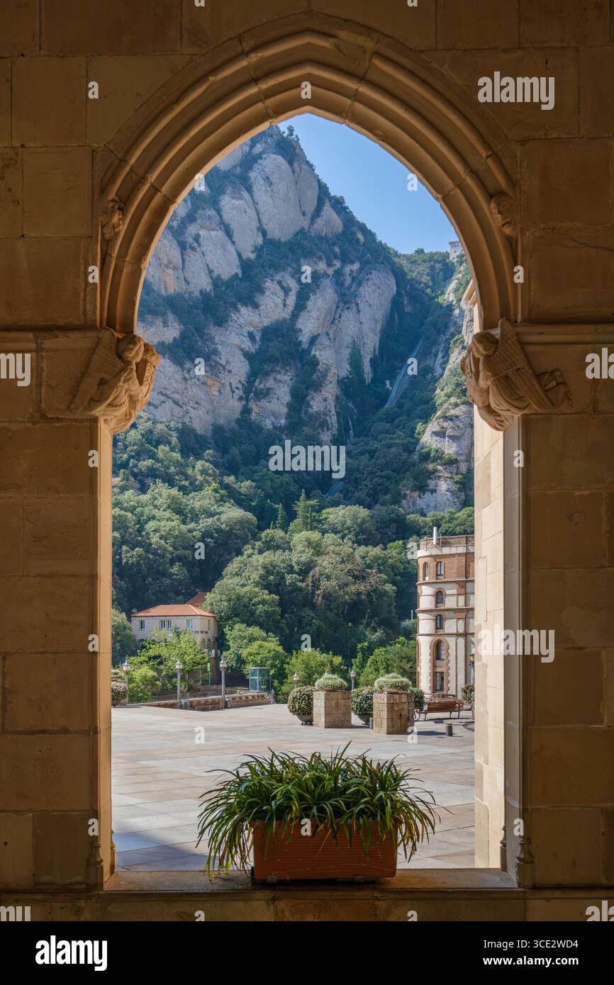 Montserrat Mountain View Through Gothic Stone Arch Window In Monastery Corridor. Medieval Architecture, Rock Formations, Religious Heritage Site Stock Photo