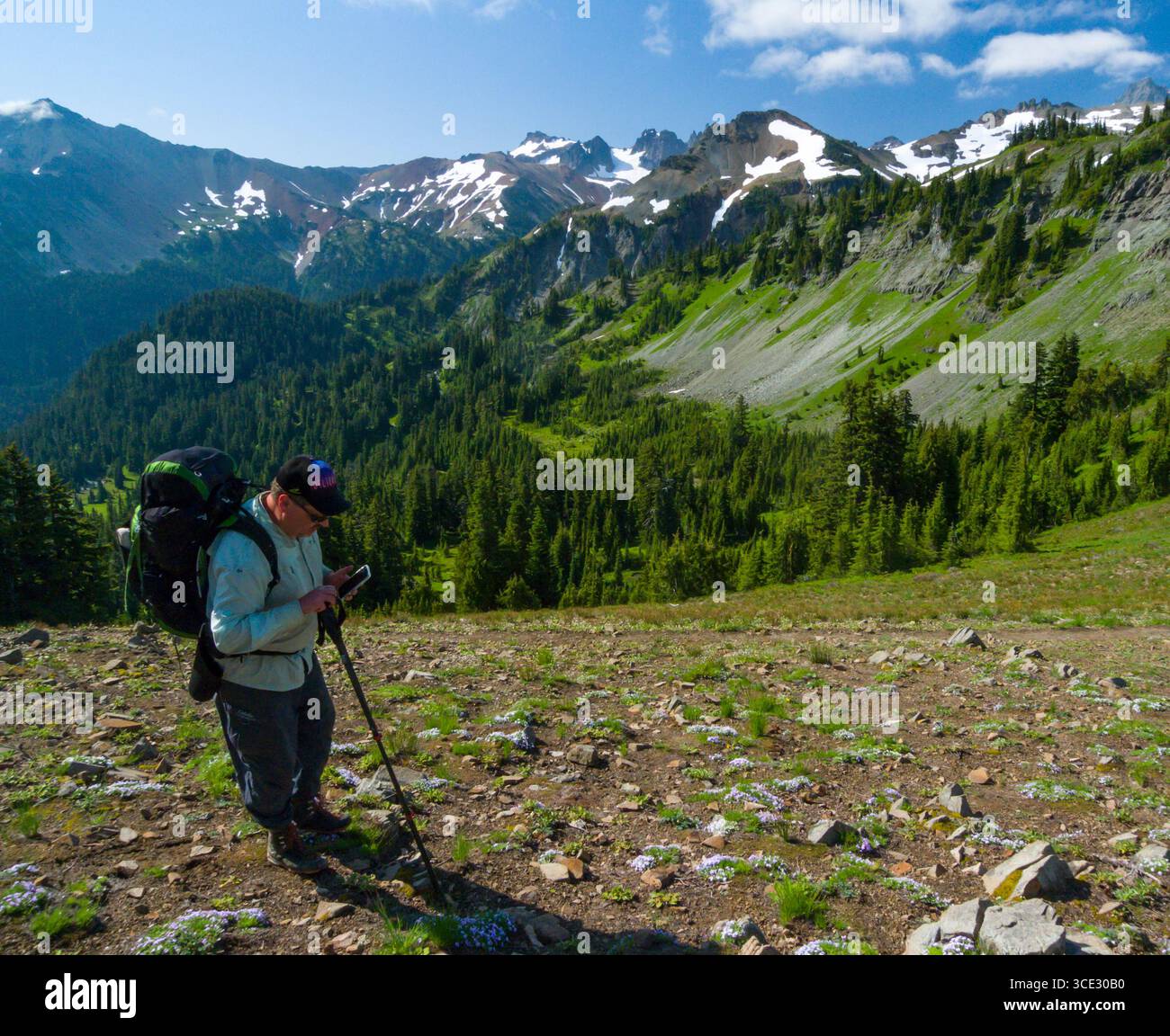 Giffer Rocks Male backpacker looking at his smartphone that he uses for navigation ...