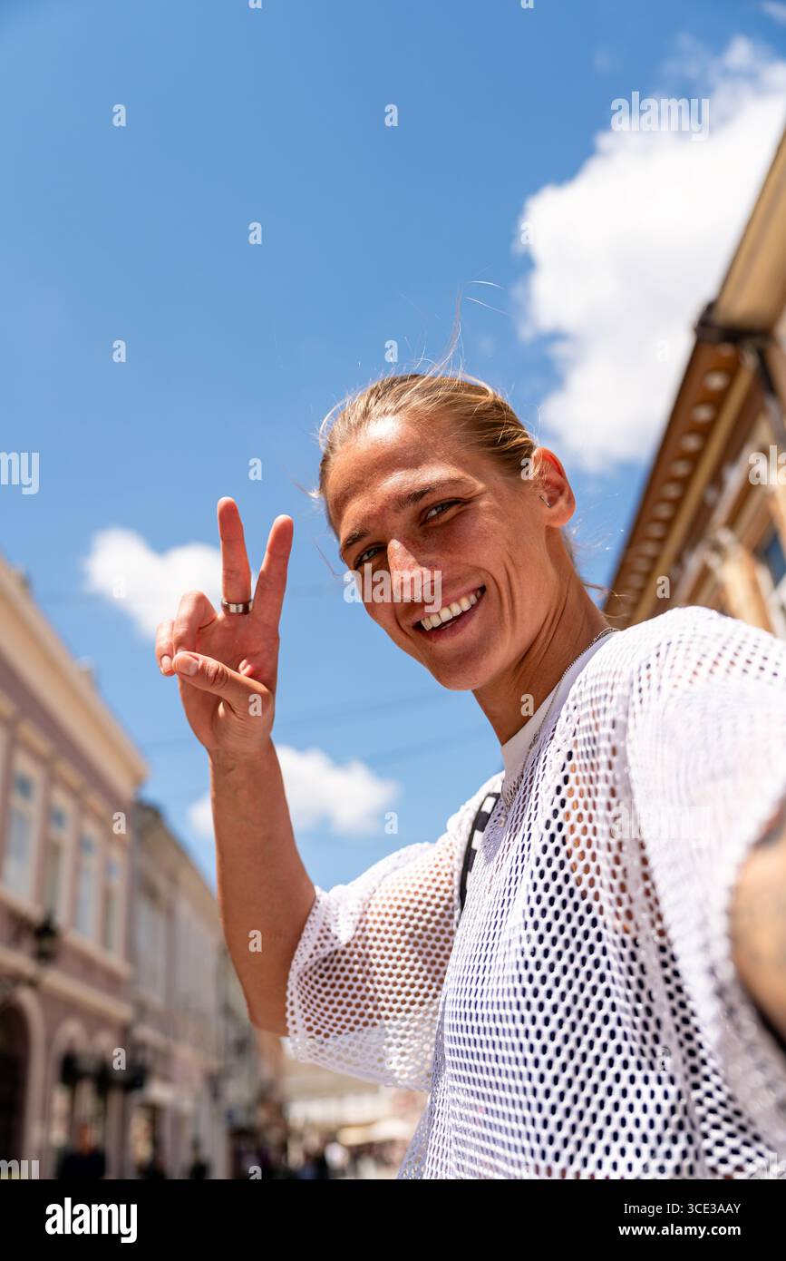 Low-angle self-portrait of smiling female traveler showing peace sign Stock Photo