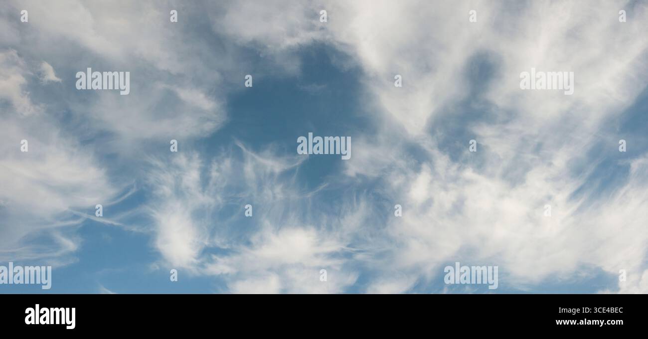 Wispy White Clouds in Bright Blue Sky Stock Photo